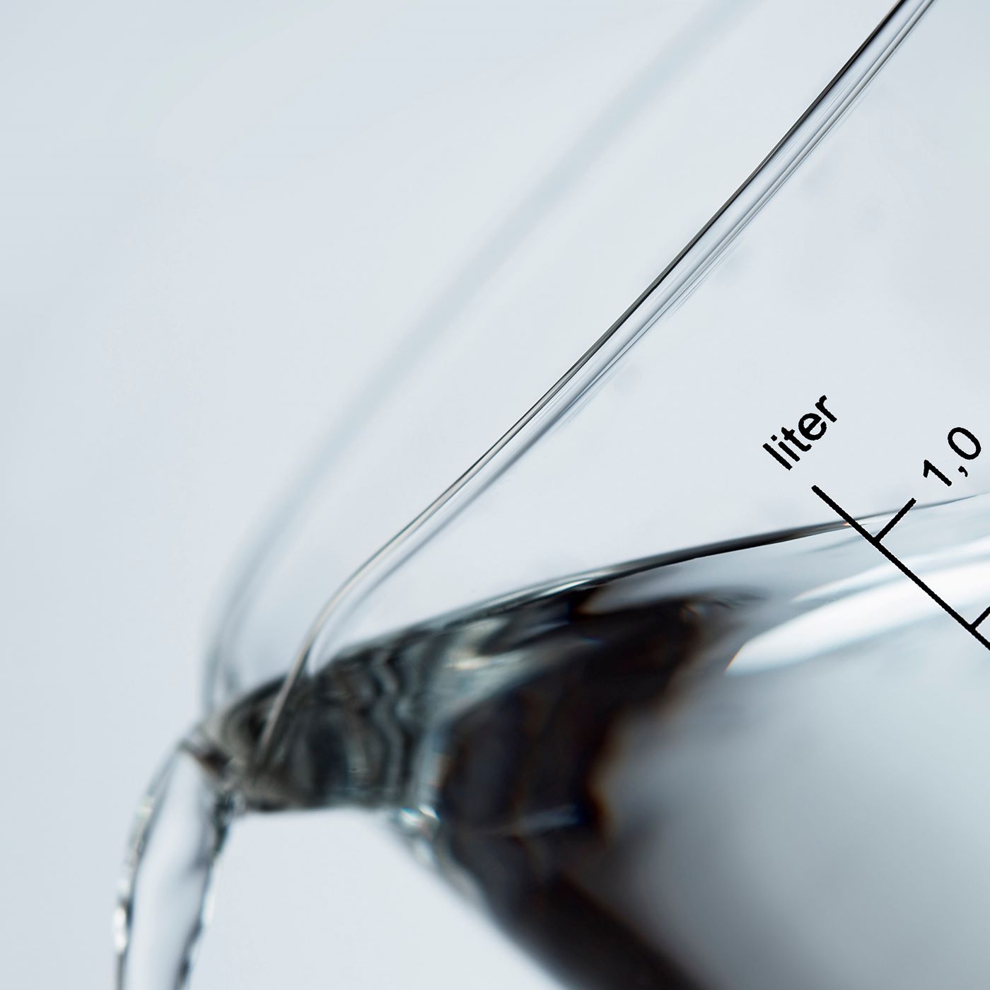 Close-up of Dame Jo! sensory oil in a glass cup with measurement markings, highlighting texture and clarity