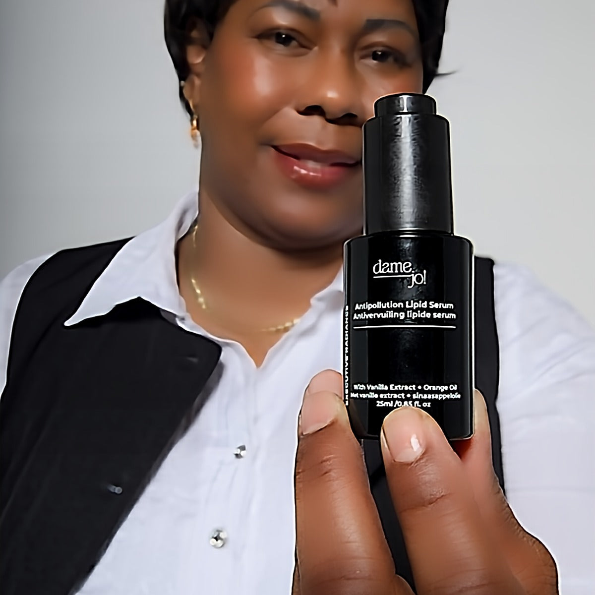 Model with luminous skin holding Executive Radiance serum in natural light